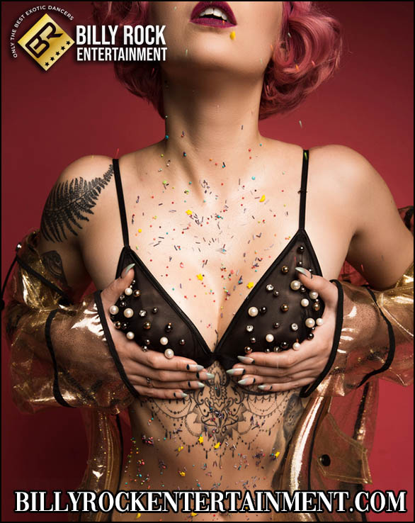Elara with a bold expression, hands on chest, showcasing artistic tattoos.