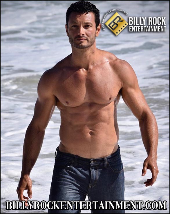 Athletic male stripper on beach in jeans, calm and confident.