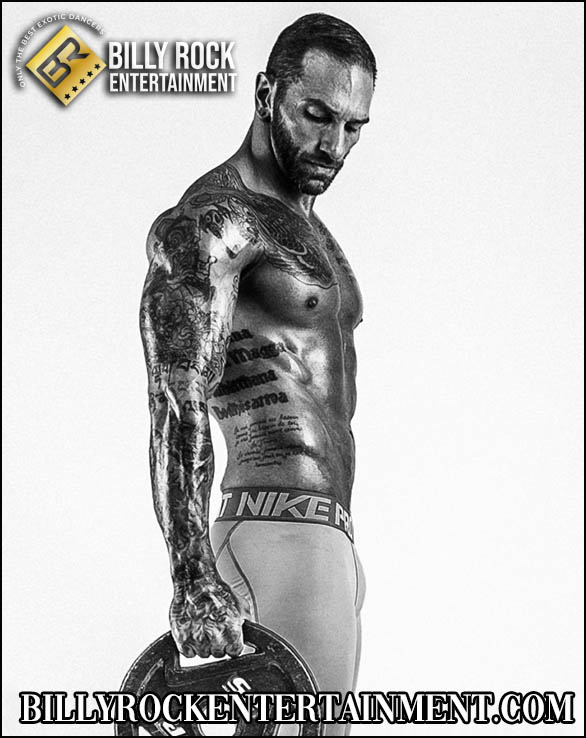 Drago: Muscular tattooed male dancer in underwear, holding a dumbbell.