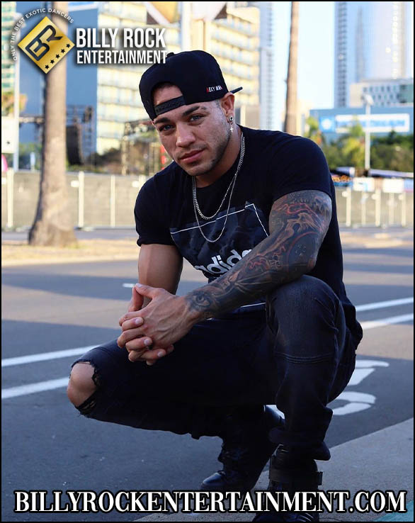 Oscar: Squatting on road, cityscape background, cap, t-shirt, ripped jeans, tattoos.