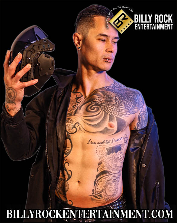 Shirtless dancer Venom with tattoos, piercings, holding a helmet, and black jacket over his shoulders.